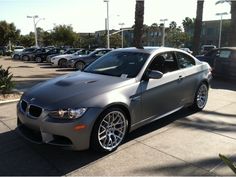 a silver car parked in a parking lot next to palm trees and other cars on the street