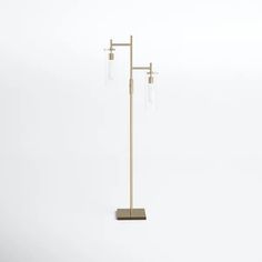 a metal and wood floor lamp with three glass shades on it's base, against a white background