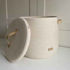 a white basket sitting on top of a table next to a wall with a wooden handle