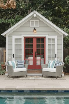 two wicker chairs sitting in front of a red door next to a swimming pool