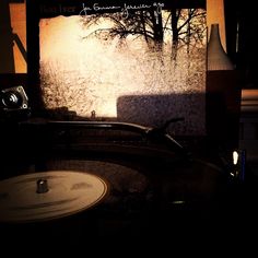 an old record player sitting on top of a table next to a wall with trees