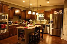 a kitchen with wooden floors and stainless steel appliances in the center, surrounded by brown cabinets