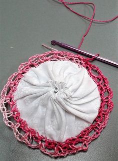 there is a crochet bag with a white cloth on it next to a knitting needle
