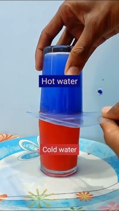 a person holding a cup with hot water in it and another hand reaching for the lid