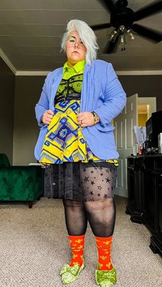 a woman with white hair and blue jacket standing in a living room wearing tights