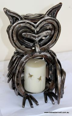 an owl candle holder is holding a lit candle