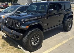 two black jeeps are parked in a parking lot