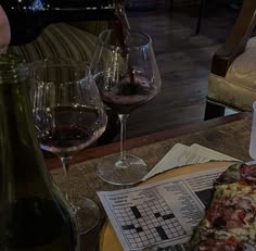 a crossword puzzle is on the table next to two wine glasses