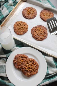 some cookies are on a plate next to a glass of milk and a spatula
