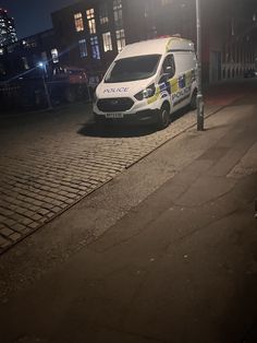 the police van is parked on the side of the road at night, with its lights on