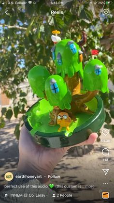 someone is holding up a green plant with little birds on it