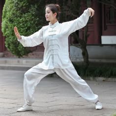a woman in white is doing karate outside