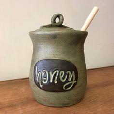 a ceramic jar with the word honey on it and a wooden spoon sticking out of it