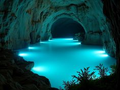 an underground cave with blue lights in the water and rocks on either side that are lit up