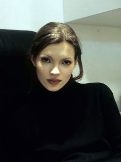 a young woman sitting in a chair with her hand on her hip and looking at the camera