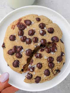 the ultimate chocolate chip cookie is cut in half and served on a white plate next to a glass of milk
