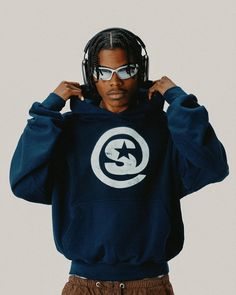 a man with dreadlocks wearing a blue hoodie and white logo on it