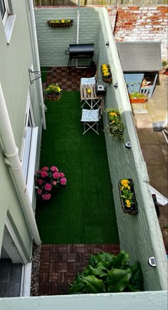an overhead view of a small backyard with flowers and plants on the grass, next to a building