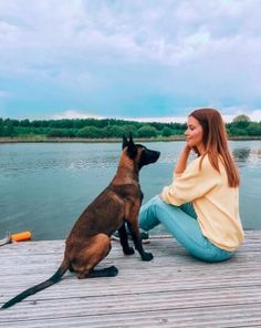 a woman sitting on a dock with her dog
