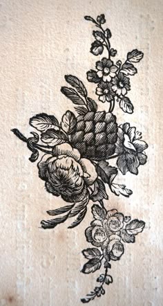 an embroidered piece of cloth with flowers and leaves in black ink on white paper background
