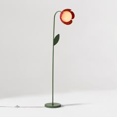 a red flower lamp sitting on top of a white table next to a corded light