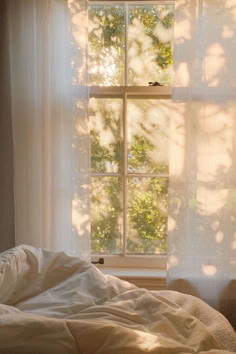 the sun is shining through the window and casting shadows on the bedding, which has a white comforter over it