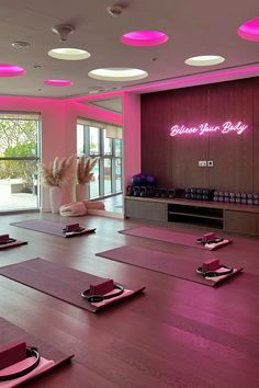 a yoga studio with pink lighting and mats on the floor