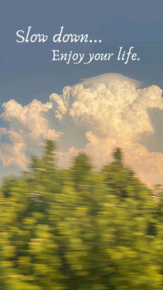 a blurry photo of trees and clouds with the words slow down enjoy your life