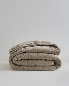 two blankets folded on top of each other in front of a white wall and floor