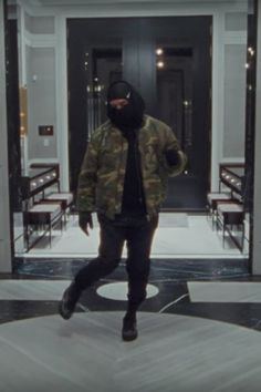 a man in a black hoodie and camouflage jacket is walking through an entrance way