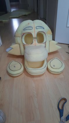 an odd looking mask sitting on top of a wooden floor next to scissors and pliers