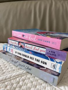 a stack of books sitting on top of a bed next to each other in front of a couch