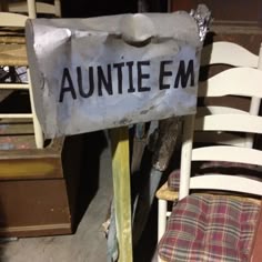 a sign that says aumite em sitting on top of a chair in a cluttered room