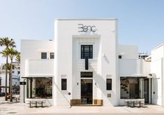 a white building with palm trees in front of it and the words one written on the door