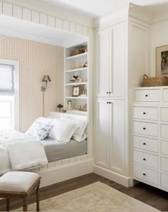 a white bed sitting in a bedroom next to a dresser under a window on top of a hard wood floor
