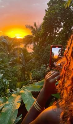 a woman is taking a photo with her cell phone in the jungle at sunset or dawn