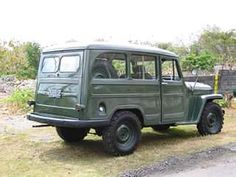 an old green truck is parked on the grass