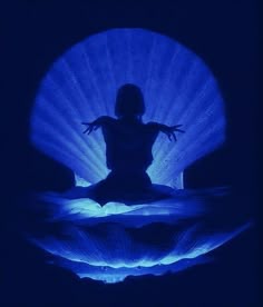 the silhouette of a person sitting in front of a blue light