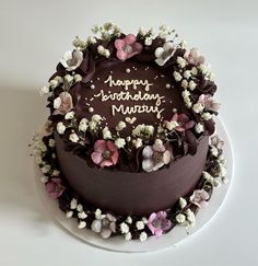 a chocolate birthday cake with white and pink flowers