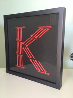 the letter k is made out of neon red plastic strips and sticks on a black frame
