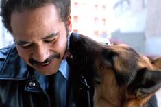 a man in a leather jacket kissing a dog