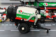 toy trucks are lined up on a table with other toys in the background and one truck has a hose attached to it