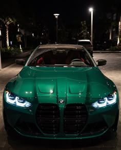 a green sports car is parked on the side of the road at night with its lights on