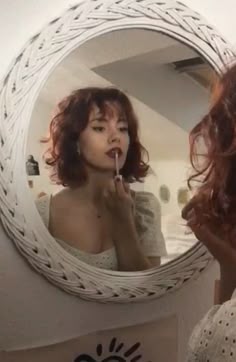 a woman is brushing her teeth in front of a mirror with the reflection of herself