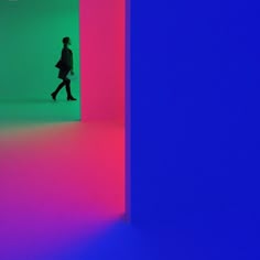 a person walking down a brightly lit room in front of a blue and pink wall