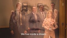 a group of people standing next to each other in front of pictures on the wall