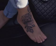 a woman's foot with a rose tattoo on it