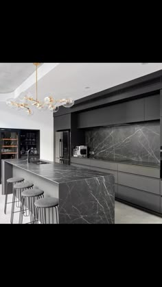 a large kitchen with marble counter tops and black cabinets, along with bar stools