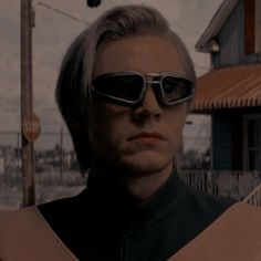 a man with sunglasses on standing in front of a building