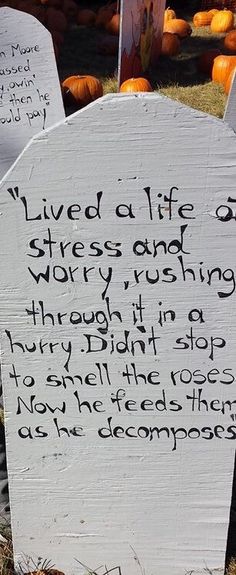 two wooden signs with writing on them sitting in the grass next to some pumpkins